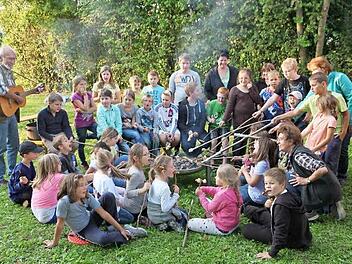 Während die Kinder nur Augen für ihr Stockbrot haben, spielt Roland Kaplan (l.) auf der Gitarre.  Foto: Galster
