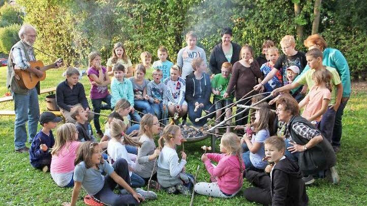 Während die Kinder nur Augen für ihr Stockbrot haben, spielt Roland Kaplan (l.) auf der Gitarre.  Foto: Galster
