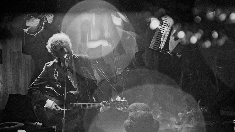 Songwriter-Legende Bob Dylan spielt einige ihrer gr&ouml;&szlig;ten Hits mit einer akustischen Live-Band im Retro-Look. Die Location: eine Bar voller rauchender und trinkender Menschen aus den 30-ern oder 40-ern.