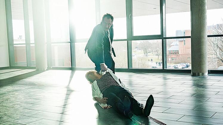 Thomas Peters (Thorsten Merten) zieht in "Ein Tag wie jeder andere" die verwundete Katrin Tscherna (Katharina Spiering) über den Boden des Universitätsflurs.