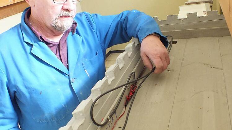 Manfred Lukasch mit neuer LED-Verkabelung an einem Gebäude der Kirchenkrippe Foto: Manfred Welker