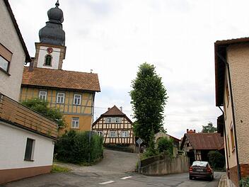 Im Zuge des Ausbaus der Bergstraße in Autenhausen lässt das Landratsamt auf Höhe der Kirche eine neue Stützmauer errichten. Für diese müssen das Kriegerdenkmal versetzt und die Linde gefällt werden, informierten die Verantwortlichen bei einer Bürgerversammlung im Sportheim. Weil ein Gehweg die Verkehrssicherheit in der Engstelle verbessern soll, wird zukünftig eine Ampel den Begegnungsverkehr dort auf ein Minimum reduzieren. Foto: Bettina Knauth