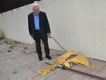 Kirchenpfleger Hans Möckel tut es im Herzen weh, die vom Kirchturm gewehten Teile (Schiff und Kruzifix) vor sich am Boden liegen zu sehen. Der Sturm fegte das Ensemble aus der Verankerung.  Fotos: K.-H. Hofmann