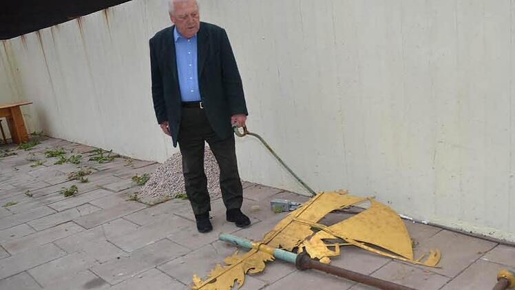 Kirchenpfleger Hans Möckel tut es im Herzen weh, die vom Kirchturm gewehten Teile (Schiff und Kruzifix) vor sich am Boden liegen zu sehen. Der Sturm fegte das Ensemble aus der Verankerung.  Fotos: K.-H. Hofmann