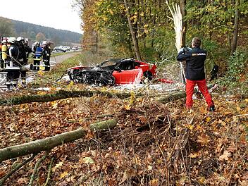 Bei Neundorf ist ein Auto von der Fahrbahn abgekommen und ist am Waldrand in Brand geraten.  Foto: Richard Sänger