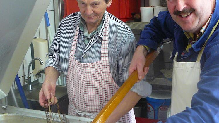 Helmut Baumer (links) und Franz Ott nehmen das gekochte Fleisch aus dem Kessel, um es Klaus Witzgall, Winfried Baumgärtner und Matthias Kummer zum Zuschneiden für den Pressack zu reichen. Fotos: Klaus-Peter Wulf