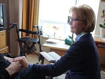 Hannelore Schwarzmann hält die Hand eines Mannes, den sie regelmäßig im Altenheim besucht.  Foto: Andreas Schmitt