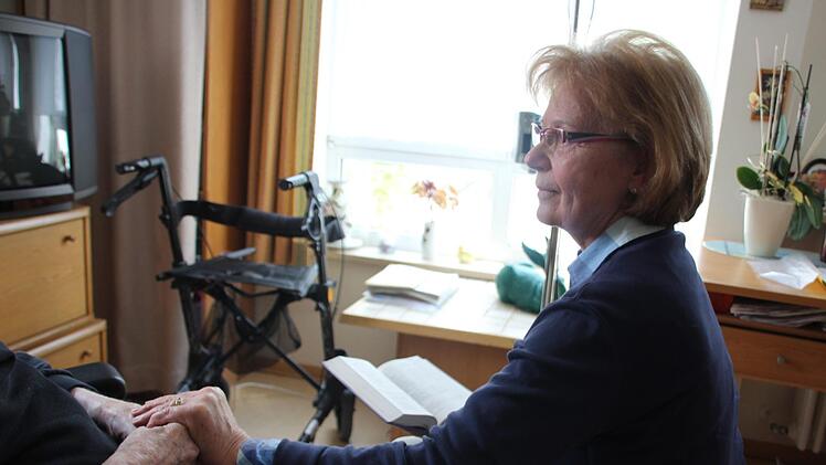 Hannelore Schwarzmann hält die Hand eines Mannes, den sie regelmäßig im Altenheim besucht.  Foto: Andreas Schmitt