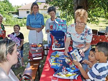Abdolhadi und Adam (rechts) packen den Schulranzen aus, Nele (mit Schultüte) schaut zu. Herzogenauracher Kinder wurden vom Verein "Weihnachtskürbis" beschenkt. Anette Hagen und Heike Krämer (von rechts) helfen mit. 3000 Euro hat Eva Zurek (daneben) zusätzlich aus Stiftungsgeldern mitgebracht. Links hinten Gastgeberin Anita Groß.  Foto: Bernhard Panzer
