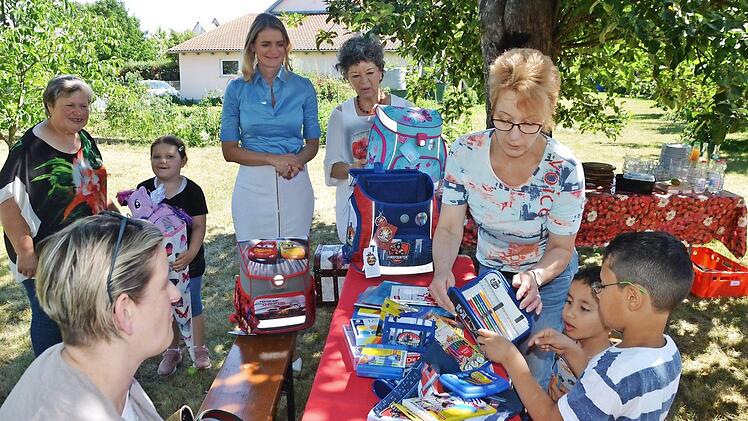 Abdolhadi und Adam (rechts) packen den Schulranzen aus, Nele (mit Schultüte) schaut zu. Herzogenauracher Kinder wurden vom Verein "Weihnachtskürbis" beschenkt. Anette Hagen und Heike Krämer (von rechts) helfen mit. 3000 Euro hat Eva Zurek (daneben) zusätzlich aus Stiftungsgeldern mitgebracht. Links hinten Gastgeberin Anita Groß.  Foto: Bernhard Panzer