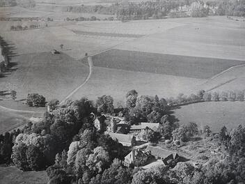 1957, als dieses Bild entstand, war das Gut Oberau noch von Wiesen und Feldern umgeben.  1961 wurde mit der Kiesgewinnung begonnen. Heute ist das Schloss von einer Seenlandschaft umgeben.Archiv v. Dungern