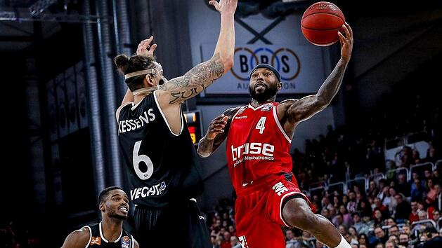 Bambergs Tyrese Rice steigt zum Korbleger gegen Vechtas Center Michael Kessens hoch; links Aufbauspieler Josh Young. Daniel L&ouml;b