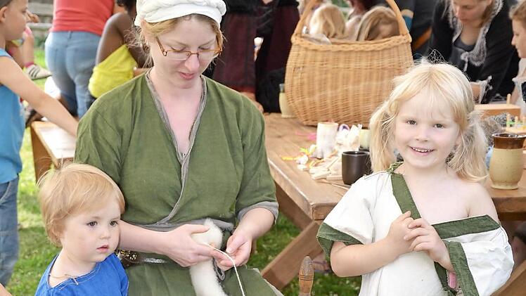 Eine junge Frau spinnt Wolle. Auch die Kleidung erinnert an das Mittelalter. Foto: Keul