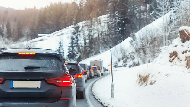 Viele Autos stecken auf einer Bergstra&szlig;e im den Alpen im Stau fest, an einem kalten Wintertag in einem europ&auml;ischen Bergkurort. Autounfall, Fahrzeug, Rushhour, Zusammenbruch. Urlaub, Transport, saisonal, feststecken.