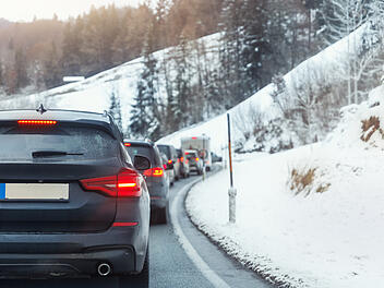 Viele Autos stecken auf einer Bergstra&szlig;e im den Alpen im Stau fest, an einem kalten Wintertag in einem europ&auml;ischen Bergkurort. Autounfall, Fahrzeug, Rushhour, Zusammenbruch. Urlaub, Transport, saisonal, feststecken.