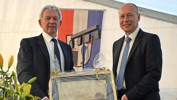 Landrat Kalb (links) überreichte Bürgermeister Karmann (rechts ) einen Faksimile-Druck der Originalurkunde von 1118. Foto: Andrea Spörlein