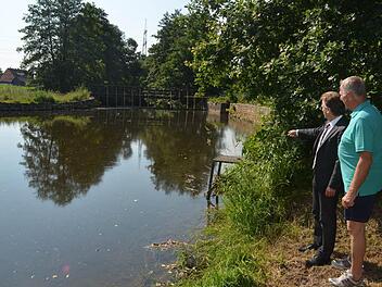Das Wehr in der Haßlach dient der Ableitung eines Teils des Wassers der Haßlach in den Mühlbach, der für ein Holzsägewerk genutzt wird. Bei Hochwasser kann dies extrem gefährlich werden, wenn das Wehr nicht rechtzeitig geöffnet wird, verdeutlicht Anwohner Klaus Scherer (rechts) Bürgermeister Rainer Detsch. Scherer hat die Überflutung 1967 in seinem Garten miterlebt. Das Wasser ging seinen Weg durch die Straßen und Gärten, so etwas möchte Scherer nicht wieder haben. Foto: K.-H. Hofmann