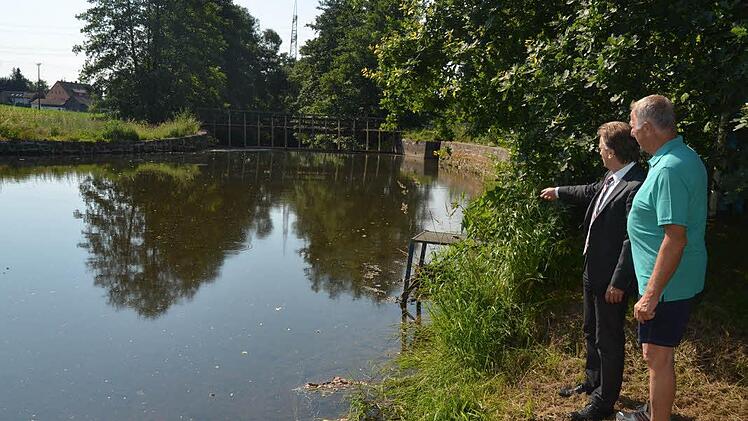Das Wehr in der Haßlach dient der Ableitung eines Teils des Wassers der Haßlach in den Mühlbach, der für ein Holzsägewerk genutzt wird. Bei Hochwasser kann dies extrem gefährlich werden, wenn das Wehr nicht rechtzeitig geöffnet wird, verdeutlicht Anwohner Klaus Scherer (rechts) Bürgermeister Rainer Detsch. Scherer hat die Überflutung 1967 in seinem Garten miterlebt. Das Wasser ging seinen Weg durch die Straßen und Gärten, so etwas möchte Scherer nicht wieder haben. Foto: K.-H. Hofmann