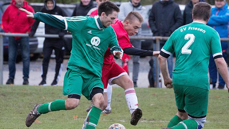 Der Neukenrother Torsch&uuml;tze Niklas Wich (rotes Trikot) setzt zum Torschuss an und Friesens Philipp Geiger versucht noch den Fu&szlig; vor den Ball zu bekommen.  Foto: Heinrich Wei&szlig;