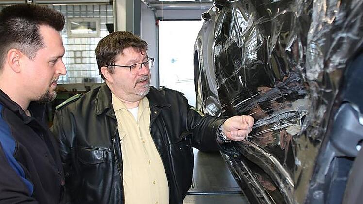 Kfz-Meister Alexander M&uuml;ller und Polizist Joachim Reininger begutachten einen Schaden: Wenn es sich hier um eine Unfallflucht gehandelt h&auml;tte, w&uuml;rde die eingeklemmte Glasscherbe vom gegnerischen Fahrzeug R&uuml;ckschl&uuml;sse auf die Fahrzeugmarke zulassen. Foto: Ralf Ruppert