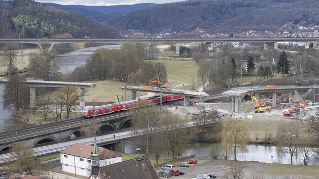 Kurioser Anblick in Gem&uuml;nden: Beim Abriss des ersten Teilst&uuml;cks der Mainbr&uuml;cke st&uuml;rzte ein Teil zu viel ein. Jetzt steht ein Bagger isoliert da. Doch Z&uuml;ge k&ouml;nnen dennoch unten durchfahren. Foto: Jens Jedamzik