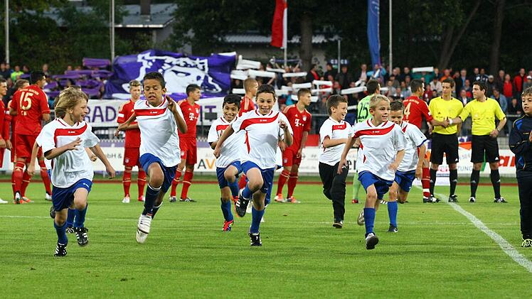 Mit Volldampf sausen die Einlaufkinder vom Rasen, w&auml;hrend im Hintergrund  die Vorbereitungen  f&uuml;r den Ansto&szlig; laufen.