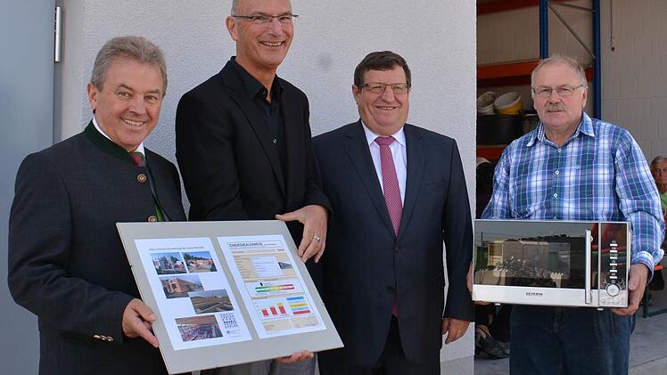 Keinen Schlüssel, sondern einen Energieausweis gab es bei der Übergabe des neuen Wülfershäuser Bauhofs für Bürgermeister Peter Schön. von Architekt Volker Eppler. Bauhofleiter Lorenz Bauer (rechts) freute sich über die neue Mikrowelle. Stellvertretender Landrat Josef Demar lobte das neue Bauwerk, das für Wülfershausen maßgeschneidert sei. Foto: Friedrich