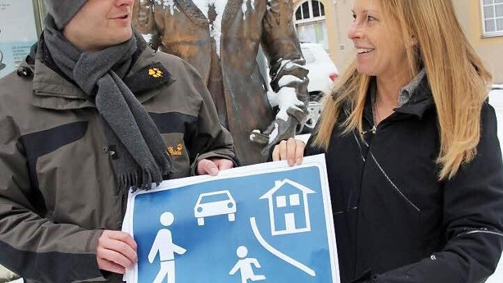 Christian Ziegler und Sabine Scheer halten einen Ausdruck mit einem Schild in der Hand, wie es an verkehrsberuhigten Straßen steht. Eine solche Zone soll auch die Bahnhofstraße in Bad Staffelstein werden, meinen die Jungen Bürger. Fotos: Tobias Kindermann