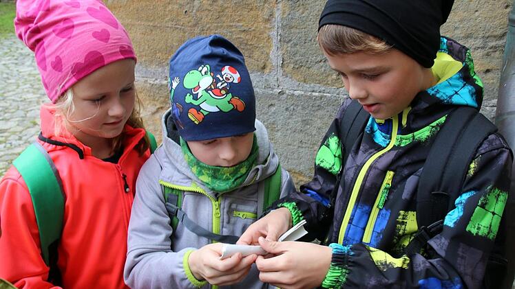 Eine Geocaching-Tour auf Martin Luthers Spuren bietet jetzt die Initiative Rodachtal in Heldburg an. Am Donnerstag konnten Schüler der Grundschule Hellingen sie erstmals testen. Gespannt entrollen Nick, Lukas und Helene (von rechts) den im ersten Cache versteckten Text. Foto: Bettina Knauth