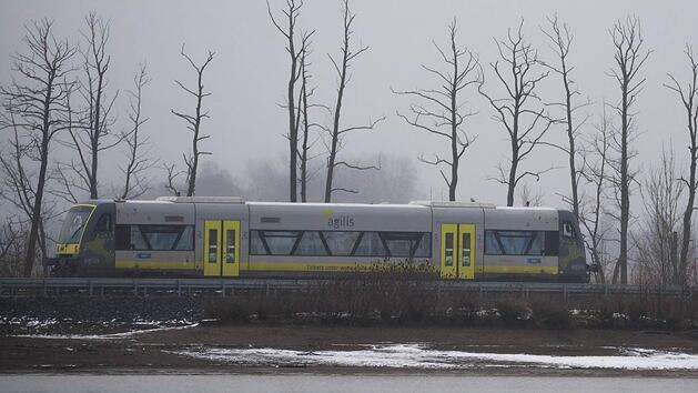 Bei grauem und regnerischem Wetter f&auml;hrt in Coburg ein Regionalzug dder agilis-Verkehrsgesellschaft am Goldbergsee entlang. Foto: Nicolas Armer/dpa