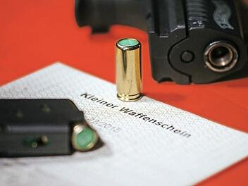 Ein Kleiner Waffenschein liegt zwischen einer Schreckschuss-Pistole Walther P22, einem Magazin und einer Platzpatrone.  Foto: Oliver Killig , dpa