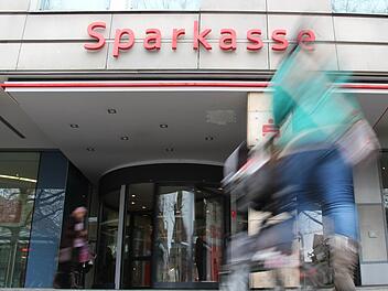 Eine Mutter mit Kinderwagen steuert den Haupteingang der Sparkasse am Hugenottenplatz in Erlangen an. Foto: Christian Bauriedel
