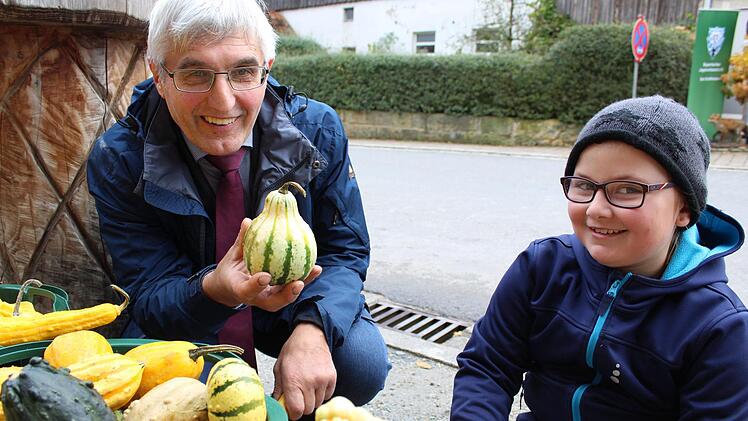 Hans-Jürgen Rebelein erfreut sich mit einer kleinen Uetzinger Besucherin an schmucken Ernteerzeugnissen.