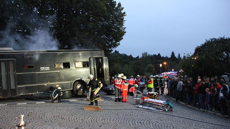 Gespannte Zuschauer beobachten die Unfallszenerie. Rüsthölzer werden an die Einsatzstelle gebracht, um das Fahrzeug zu unterbauen. Foto: Mariell Dörrschmidt