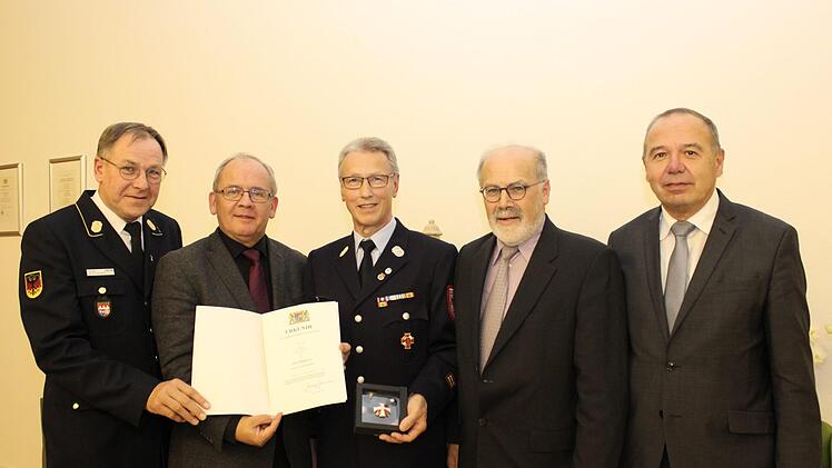 Regierungspr&auml;sident Dr. Eugen Ehmann (2. von links) bei der Aush&auml;ndigung des Steckkreuzes f&uuml;r besondere Verdienste um das Feuerwehrwesen an Klaus W&uuml;scher (Mitte) im Beisein des Stellvertreters des Landrats des Landkreises Bad Kissingen J&uuml;rgen Englert (rechts), des Ersten B&uuml;rgermeisters des Marktes Sulzthal August Weingart (2. von rechts) und des Vorsitzenden des Bezirksfeuerwehrverbandes Unterfranken Benno Metz (links).  Foto: Nicolas Rupp