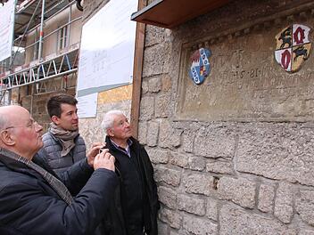 Dr. Manfred Scholz (von links), Max Warmuth und Karl Warmuth betrachten die Steintafel am Ortseingang von Sulzthal, die an den Bau der Dorfmauer unter dem damaligen "Schultes Hansen Warmut" erinnert. Foto: Ralf Ruppert