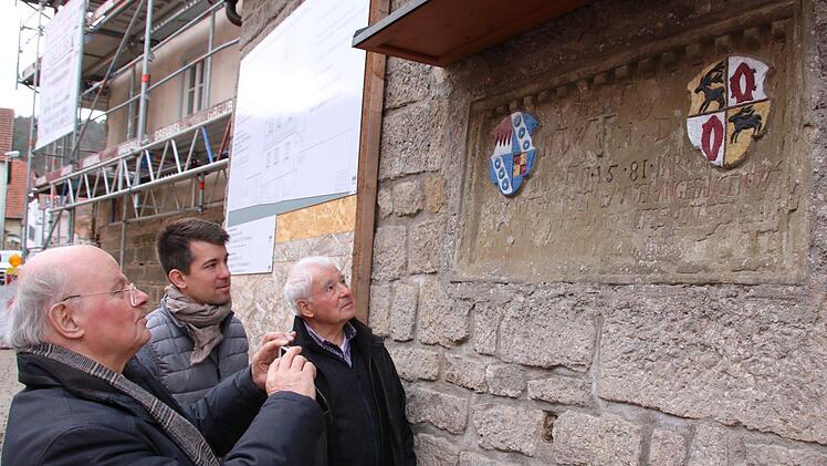 Dr. Manfred Scholz (von links), Max Warmuth und Karl Warmuth betrachten die Steintafel am Ortseingang von Sulzthal, die an den Bau der Dorfmauer unter dem damaligen "Schultes Hansen Warmut" erinnert. Foto: Ralf Ruppert