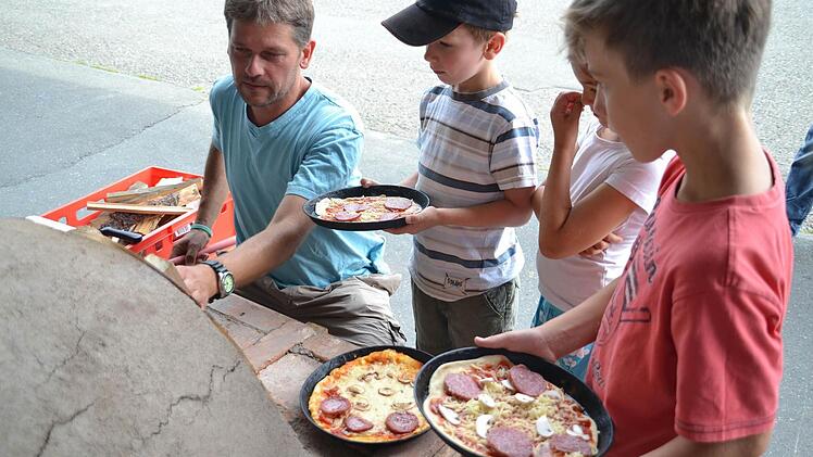 Nach und nach wanderten die Pizzen in den Lehmofen. Von links: Oliver Leimenstoll, Maximilian, Jule und Marlon. Fotos: Uschi Prawitz