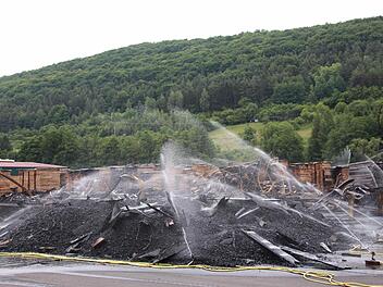 Mehr als 40 Stunden nach Ausbruch des Feuers in einer Holzlagerhalle des Untererthaler Sägerwerks kühlen Wassersprenger die Brandstelle weiter ab. Es gibt immer noch Glutnester. Foto: Benedikt Borst