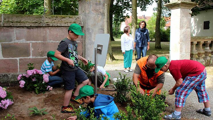 Markus Großkopf (2. v. r.) erklärte den Kindern, wie sie die Pflanzen richtig in den Boden bringen. Im Hintergrund freuten sich Schulleiterin Sieglinde Gröger (l.) und Lehrerin Eva Schlegel über die gelungene Aktion. Fotos: Johanna Blum