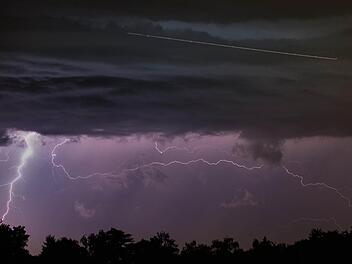Blitze zeichnen sich am 24.07.2014 am nächtlichen Himmel südlich von Frankfurt am Main (Hessen) bei einem Gewitter ab. Vor den dunklen Wolken (o.) hinterlässt ein letztes startendes Flugzeug seine Spur während der zehnsekündigen Belichtung. Foto: Frank Rumpenhorst/dpa