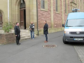 Pfarrer Norbert Wahler, Bauhofangestellter Christian Reusch und Bürgermeister Johannes Krumm (von links) lauschen neben dem BR-Aufnahmefahrzeug dem Zwölf-Uhr-Läuten.