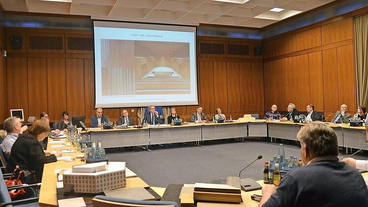 Stadtratsdebatte im holzvertäfelten (alten) Sitzungssaal über das neue Rathaus. Auch die Gestaltung des künftigen Ratssaals (siehe Fotobeispiel auf der Leinwand) war Thema. Beschlossen wurden jetzt lediglich die Materialien. Über die Ausgestaltung wird noch zu reden sein.  Foto: Bernhard Panzer