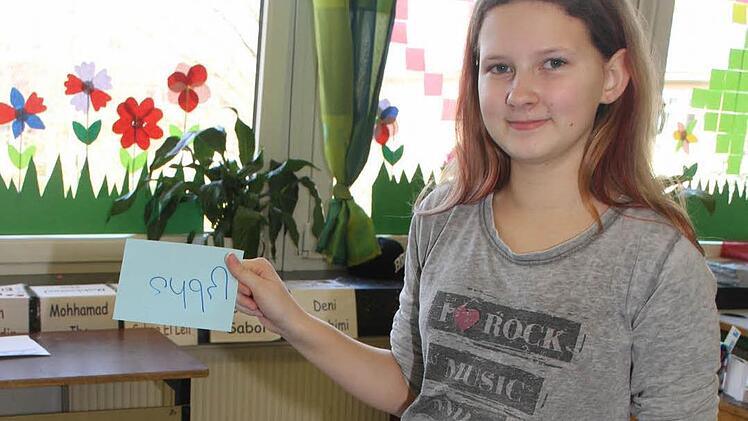 Leonie Meisel hat einen Zettel in der, auf dem eine Zahl steht, und versucht zu enträtseln, um welche es sich handeln könnte. Foto: Sonja Adam