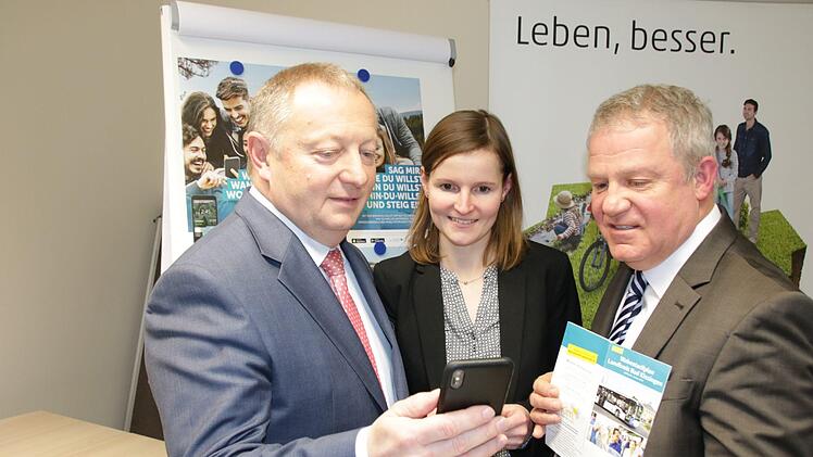 Landrat Thomas Bold (von links), Anja Baniewicz von der DB Regio Bus und Michael Schäder, Nahverkehrsbeauftragter des Kreises, schauen sich die neue Mobilitäts-App an. Die gedruckten Busfahrpläne und die Karte mit dem Wabentarif gibt der Kreis aber trotzdem weiter raus. Foto: Ralf Ruppert