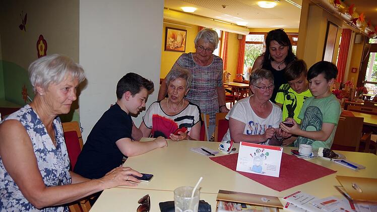 Die "Handy-Erklärer" Noel, Kilian und Luan erklären den technikaffinen Damen verschiedene Funktionen der Handys und Smartphones. Mit im Bild ist die Projektleiterin Ivonne Schmidt (rechts hinten).  Heike Schülein