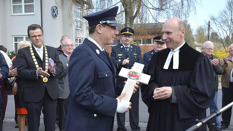 Pfarrer Stephan Aupperle überreichte an Kommandant Markus Eiring ein Kreuz mit dem Bild des Feuerwehrautos, das künftig im Feuerwehrgerätehaus seinen Platz finden wird. Links steht Bürgermeister Werner Döhler. Bild: Schmidt