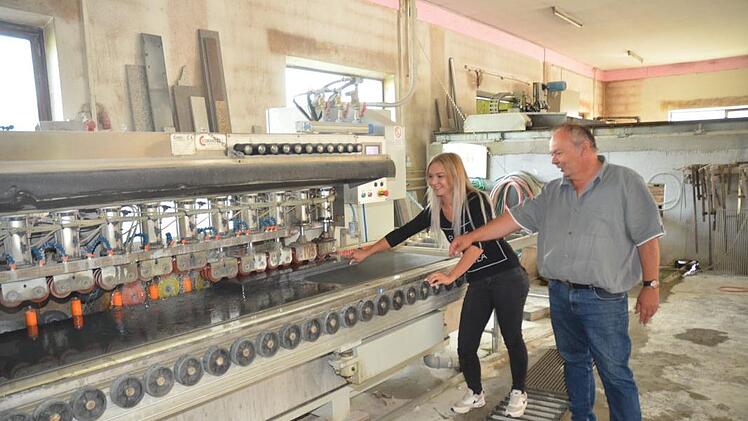 Robert Karg mit Tochter Larissa am Kantenschleifautomaten in der Werkstatt, in der Natursteine millimetergenau zugeschnitten werden. Foto: eh