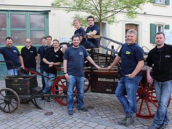 Die Mühlhausener Feuerwehr mit dem Zweiten Vorsitzenden Patrick Seidel, dem Vorsitzenden Friedel Pickel und dem Kommandanten Stephan Vogel (vordere Reihe von rechts). Sie präsentieren eine Druckspritze aus dem Jahr 1880 und die Saugdruckspritze von 1913.  Foto: Evi Seeger