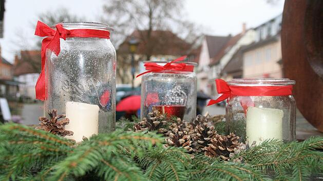 Immer ein Hingucker: Schöne Kerzengläser mit Zweigen, Schleifen und Zapfen verziert.   Foto: Anja Vorndran